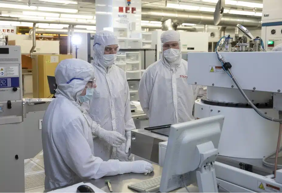 A group of people in protective suits working in a factory specializing in nano sciences.