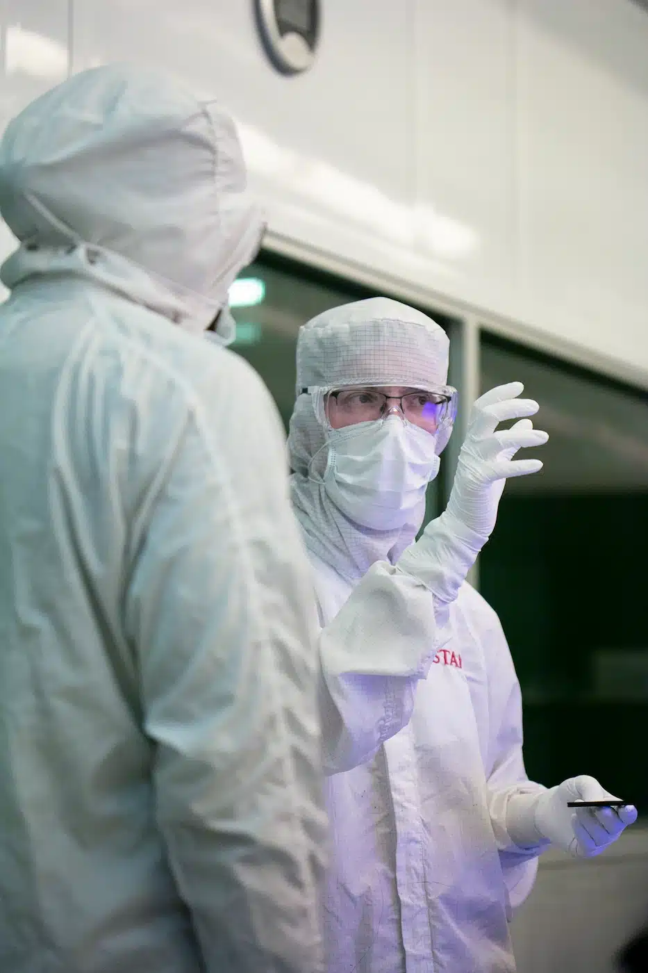 Two people in protective suits standing next to each other conducting nano sciences experiments.