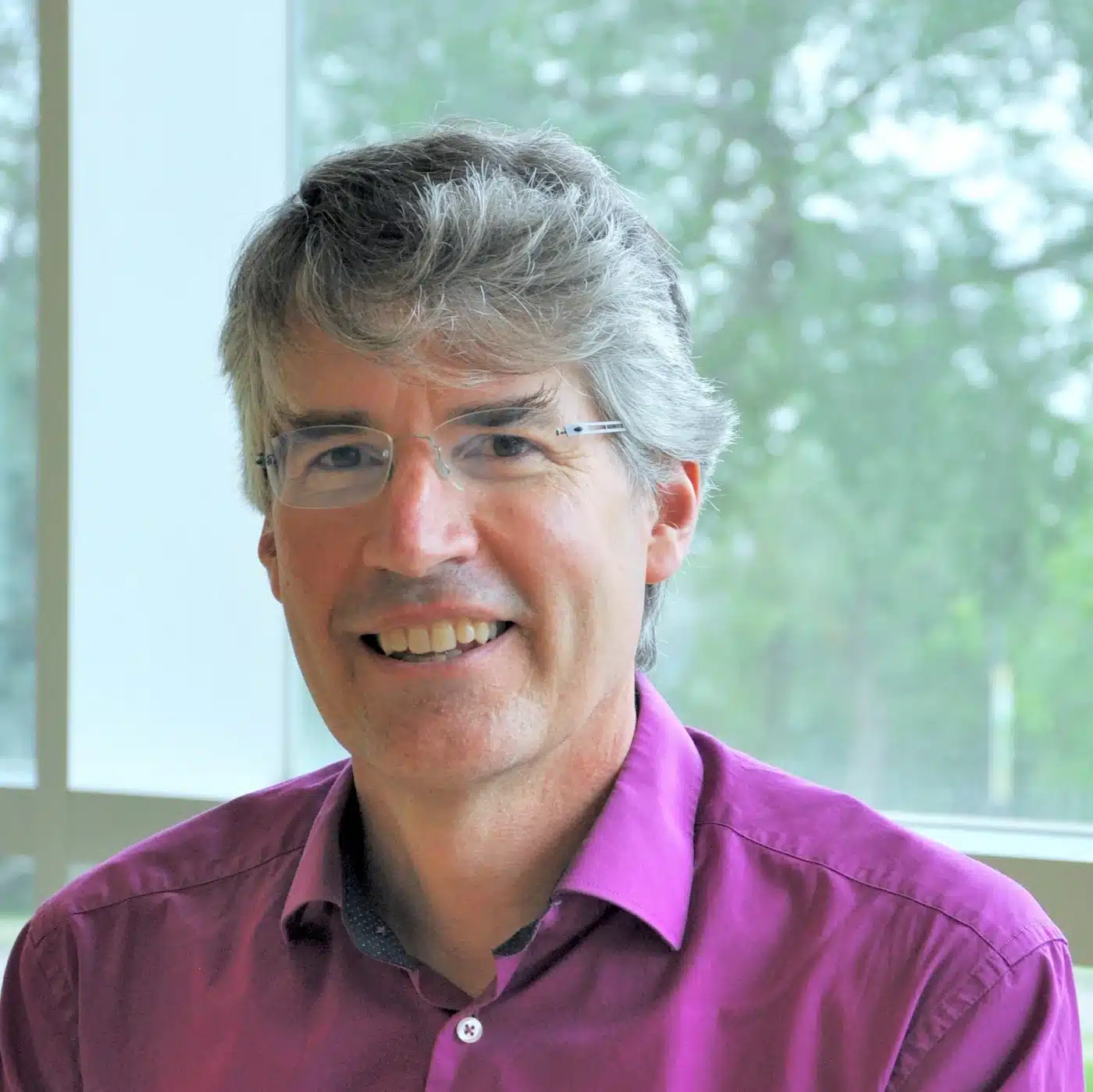 A man smiling in front of a window.